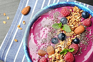 Delicious acai smoothie with granola and berries in bowl on table
