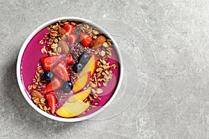 Delicious acai smoothie with granola and berries in bowl on table, top view. Space for text