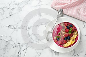 Delicious acai smoothie with granola and berries served on white marble table. Space for text