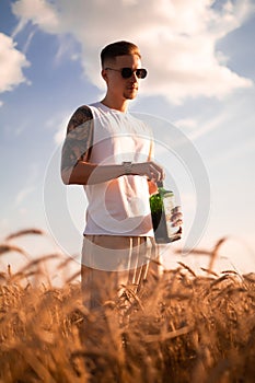 Delicious alcoholic drink in a man's hand. A farmer brewer carries fresh cold beer through a field of ripe wheat.