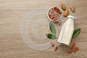 Delicious almond milk and nuts on wooden table, flat lay. Space for text