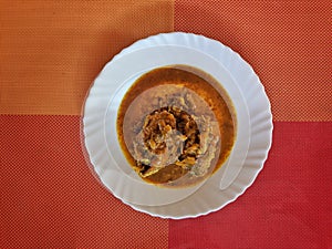 Delicious Andhra fish curry on the white plate with isolated colorfull background