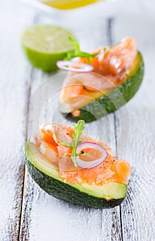 Delicious appetizer of avocado and smoked salmon on white wooden