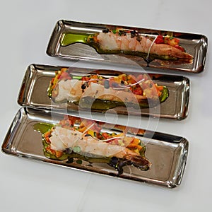 Delicious appetizer of shrimps with vegetables in chrome plates.