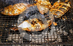 Delicious Asian fish fry served on a BBQ table. Grilled fish laid on steel grates