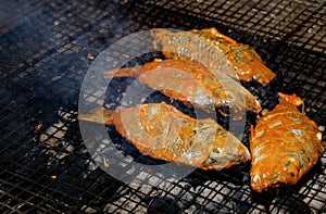 Delicious Asian fish fry served on a BBQ table. Grilled fish laid on steel grates