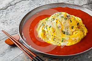 Delicious Asian tornado omelette with sesame seeds, green onions and hot pepper sauce close-up in a plate. Horizontal