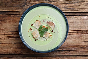 Delicious asparagus soup with croutons on wooden table, top view