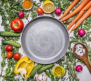 Delicious assortment of farm fresh vegetables, cucumbers, peppers, lemon, cherry tomatoes, oil, salt spoon laid around the pan