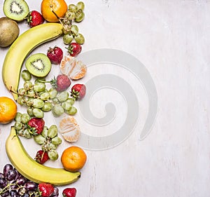 Delicious assortment of fresh fruit laid out in a border on a white rustic background top view Superfoods health or detox die