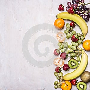 Delicious assortment of fresh fruit laid out in a border on a white rustic background top view Superfoods and health or detox die