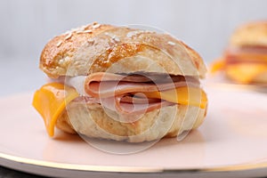 Delicious bagel with ham and cheese on plate, closeup