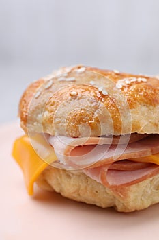 Delicious bagel with ham and cheese on plate, closeup