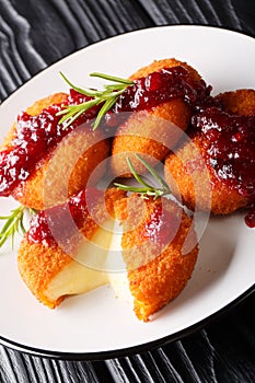 Delicious Baked Camembert Cheese Breaded with Cranberry Sauce and Rosemary closeup on a plate. vertical