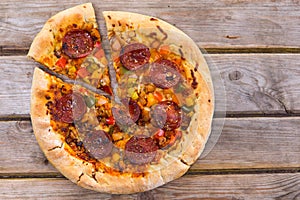 Delicious baked salami pizza served on rustic wooden table