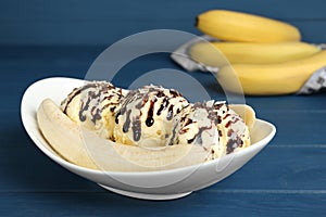 Delicious banana split ice cream on blue wooden table