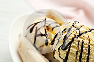 Delicious banana split ice cream with chocolate topping on plate, closeup