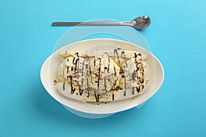 Delicious banana split ice cream with toppings on light blue background, flat lay