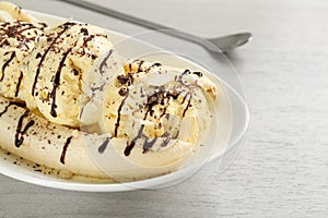 Delicious banana split ice cream with toppings on white wooden table, closeup