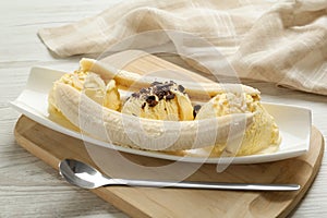 Delicious banana split ice cream with toppings on white wooden table , closeup