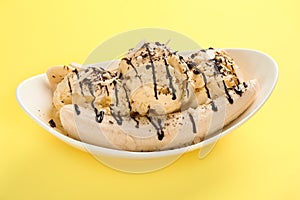 Delicious banana split ice cream with toppings on yellow background