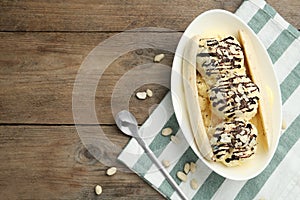 Delicious banana split ice cream on wooden table, flat lay. Space for text
