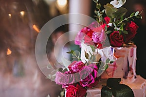 Delicious beautiful wedding cake with white cream decorated with pink and red roses and eucalyptus