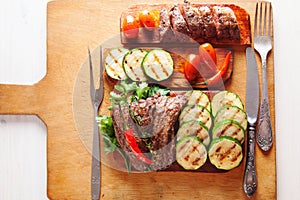 Delicious beef steak with vegetable over wooden table top view