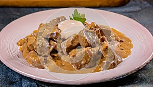 Delicious Beef Stroganoff in Creamy Sauce Garnished with Fresh Parsley on a Rustic Plate photo