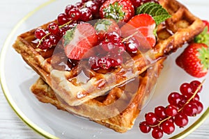 Delicious Belgian waffles with berries and honey on plate, closeup