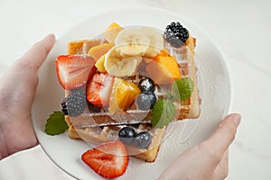 Delicious Belgian waffles with fresh Summer Fruit salad with oranges, strawberries, blueberries, kiwi and fresh mint