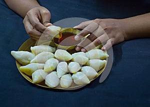 Delicious bengali rice flour coconut dumpling served during bengali indian festival of makar sankranti. hands eating dumplings