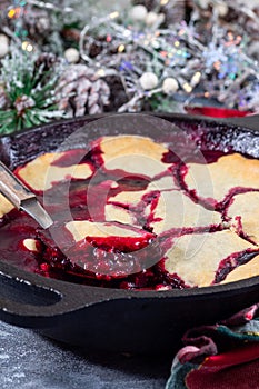 Delicious berry cobbler in cast iron skillet, Christmas decoration on background, vertical