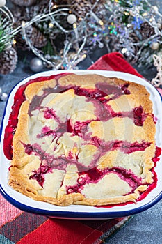 Delicious berry cobbler in enamel baking dish, Christmas decoration on background, vertical