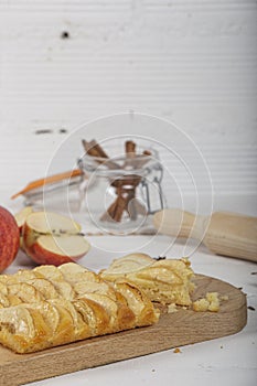 Delicious bitten apple pie on white wooden background. Vertical image