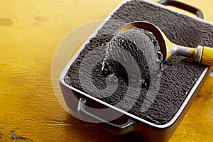 Delicious black ice cream in container with scooper