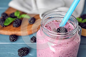 Delicious blackberry smoothie in mason jar on blue wooden table. Space for text