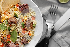 Delicious boiled rice with meat and vegetables in bowl on table, closeup