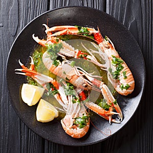 Delicious boiled scampi or langoustine or Norway lobster close-up on a plate with sauce and lemon. top view