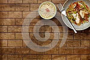 A delicious bowl of chicken chow mein, noodles and vegetables, with a fork in a rustic bowl and a side bowl of rice, shot on a