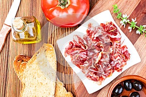 Delicious bread toast with natural tomato, extra virgin olive oil, Iberian ham, black olives and basil leaves.