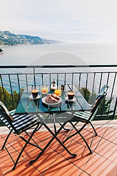 Delicious breakfast with coffee, pastry, and orange juice served on the balcony with sea view