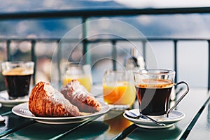 Delicious breakfast with coffee, pastry, and orange juice served on the balcony with sea view