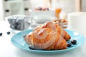 Delicious breakfast with croissants and berries on table