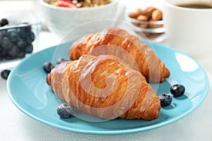 Delicious breakfast with croissants and berries on table, closeup