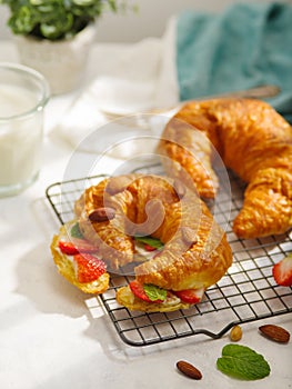 Delicious breakfast - croissants with butter, strawberries, almonds and mint leaves and fresh milk. White background. There are no