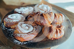 Delicious breakfast with croissants and sweets on plate on brown wooden table