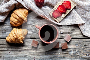 Delicious breakfast with a cup of coffee and fruit sandwiches, croissants. Strawberries, food, drink, chocolate.