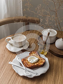 Delicious breakfast, dessert, snack - coffee and baked brioche French toast with Greek yogurt and honey on a wooden table