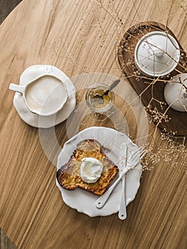 Delicious breakfast, dessert, snack - coffee and baked French toast with yogurt on a wooden table, top view